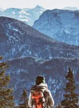 Person enjoying scenic view from mountain top with backpack.