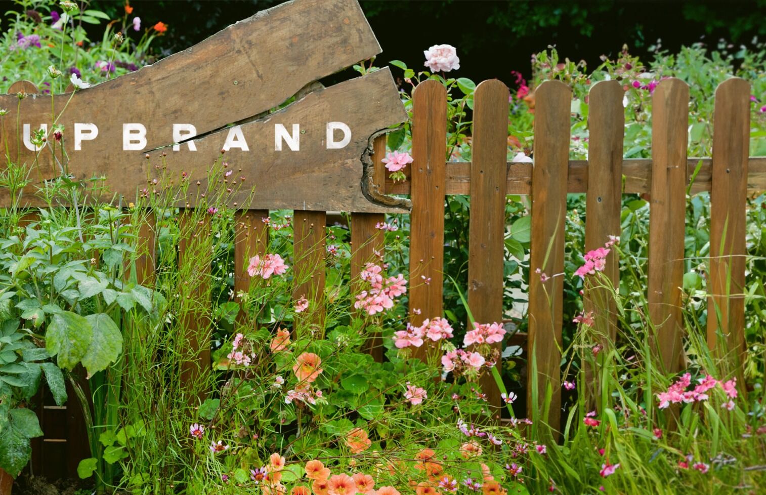  Image of a garden and wood fence with the word UPBRAND in the background