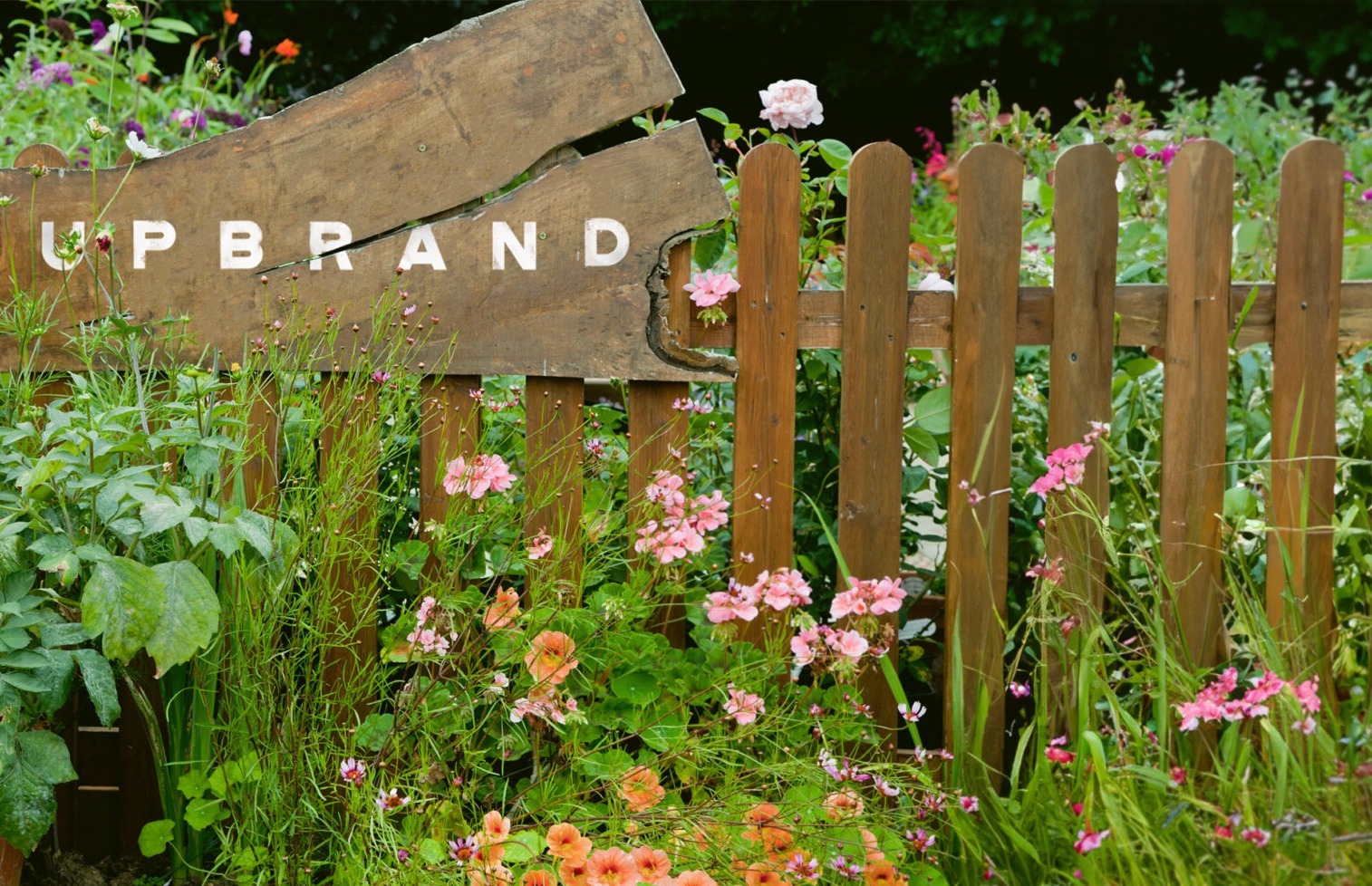  Image of a garden and wood fence with the word UPBRAND in the background