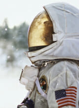 An astronaut in a white suit stands in the snow.