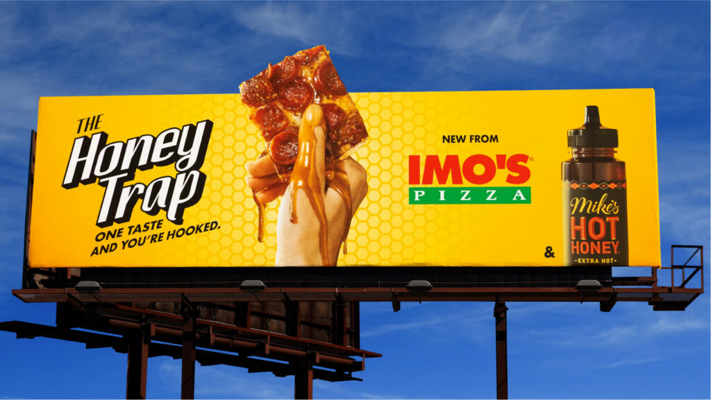 A billboard against a blue sky: The Honey Trap, one taste and you're hooked. New from Imo's Pizza and Mike's Hot Honey.